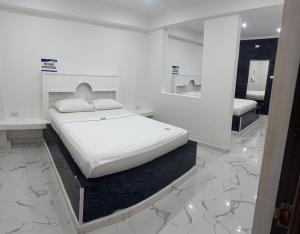 a white bedroom with a bed and a mirror at Hotel Pacífico Azul in Bahía Solano