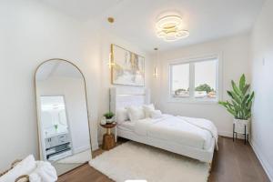 a white bedroom with a bed and a mirror at Toronto Midtown Luxury Living in Toronto