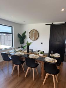 a dining room table with chairs and a clock on the wall at Darfield Retreat in Darfield