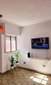 a living room with a tv on a white wall at PISO UNO - Gran Living Comedor y Habitación - PET FRIENDLY - AUTO CHECK IN 24 HS - Para 4 personas - No alquilamos a Bahienses por el momento in Bahía Blanca