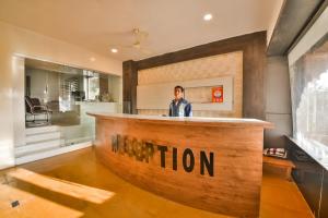 a man standing behind a wooden bar in a room at Capital O Amit Palace in Bhilwara +32 photos