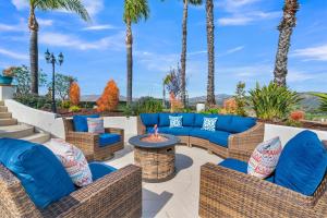a patio with wicker furniture and a fire pit with palm trees at Panorama Peak Luxury Retreat in Poway +73 photos