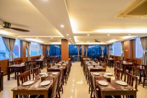 a restaurant with wooden tables and chairs and large windows at Baly Hotel Hue in Hue