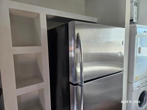 a stainless steel refrigerator in a kitchen with shelves at Modern apartment by Playas Bullring in Tijuana