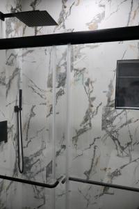 a bathroom with a shower with white marble walls at VillaLuna Studio in Wellington
