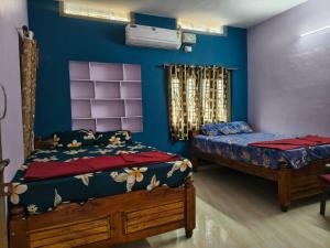 two beds in a room with blue walls at krishna yadav homestay in Hospet