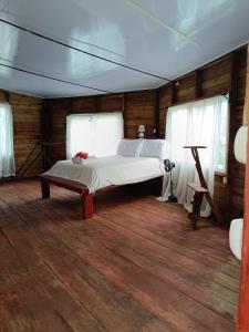 a bedroom with a bed in a room with wooden floors at Cabañas Ecológicas in Tela in Tela