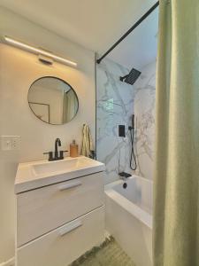 a bathroom with a sink and a tub and a mirror at North Haven Rooms in North Haven