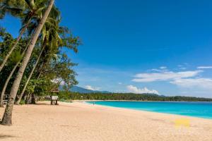 a beach with palm trees and blue water at 2BR w/mini dipping tub + 2 mins to beach in Mati