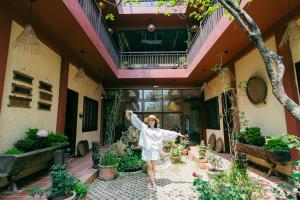 a woman standing in the courtyard of a building with her arms in the air at Về Homestay Ninh Bình in Ninh Binh