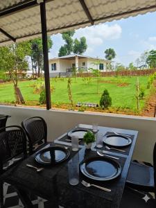 a dining table with a view of a field at Himabindu Stays in Sakleshpur