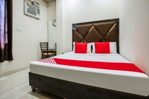 a bedroom with a large bed with red pillows at Hotel O Sunrise in Ludhiana