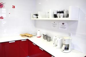 una cocina con armarios rojos y encimeras blancas en Botxo Gallery - Youth Hostel Bilbao, en Bilbao