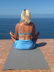 a woman sitting on a yoga mat looking at the ocean at The Sanctuary above Lo De Marcos in Lo de Marcos