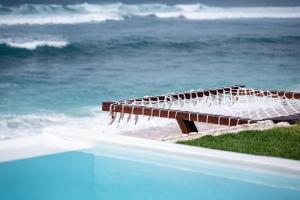 a wooden bench sitting on the beach near the ocean at Bubble 2 - Sunset Private Pool Dome Uluwatu in Uluwatu +15 photos