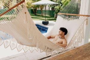 a man sitting in a hammock next to a pool at Casa La Yola in Monterrico +4 photos