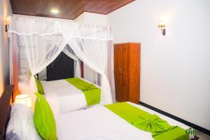 a bedroom with two beds with green and white sheets at Om Hotel in Unawatuna