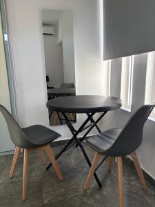 a black table and two chairs in a room at Studio tout confort avec piscine pour les amoureux des toutous in Roches Noires