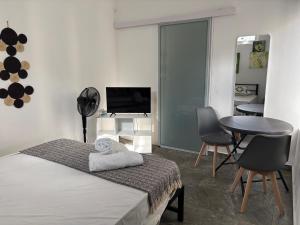 a bedroom with a bed and a table and chairs at Studio tout confort avec piscine pour les amoureux des toutous in Roches Noires
