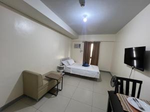 a room with a bed and a chair and a tv at Studio 7 in Manila