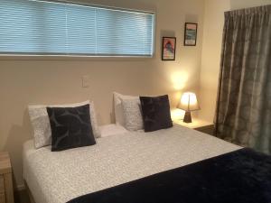 a bedroom with a bed with black and white pillows at Albert Mews B and B in Whitianga +12 photos