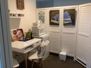 a white office with a desk and a microwave at Albert Mews B and B in Whitianga