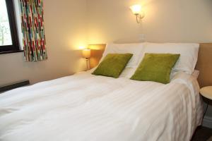 a white bed with two green pillows on it at Howe End in Mungrisdale