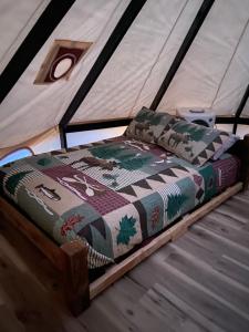 a bed in a tent with a quilt on it at Issachar Tent in Duchesne