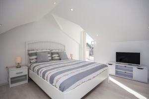a white bedroom with a large bed and a television at Apartments Dalmata in Krapanj +50 photos