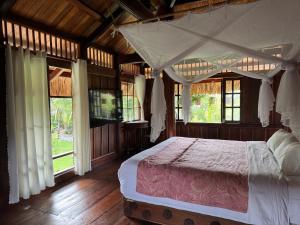 a bedroom with a canopy bed in a room with windows at Núi Dinh Stilt House - Phú Mỹ in Ấp Long Cát