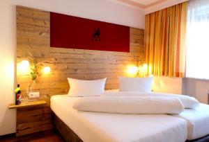 1 dormitorio con cama blanca y pared de madera en Hotel Gasthof Zum Schwanen, en Reutte