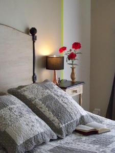 a bedroom with a bed with a lamp and a vase of flowers at La Genoise in Tillières