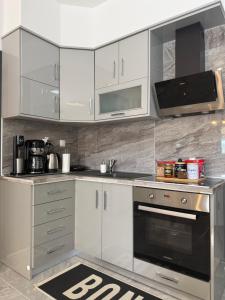 a kitchen with white cabinets and a black oven at Eunoia Homestay & BnB - Loutra Pozar, Aridaia in Aridaia
