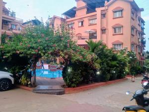a pink building with a tree with pink flowers at 1 Bhk apartment kyle garden baga beech in Baga +6 photos