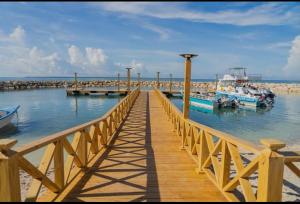 a wooden pier with boats in the water at Estilo y comodidad a pasos de la playa in La Romana