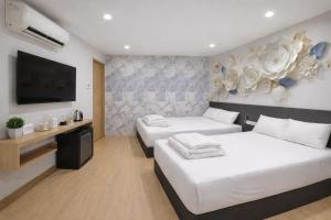 a bedroom with two beds and a flat screen tv at ARK Port Dickson Seafront Hotel in Port Dickson
