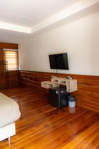 a bedroom with a television and a wooden floor at โอโซนริมน้ำเขาใหญ่ in Ban Pang Kae