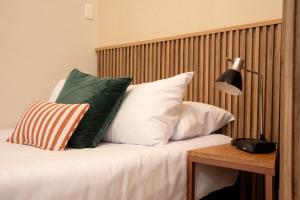 a bed with white pillows and a table with a lamp at Lima Atelier Boutique in Lima