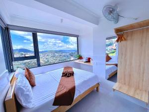 a bedroom with two beds and a large window at Villa đà lạt Trung Nghĩa 1 in Ấp Ða Lợi