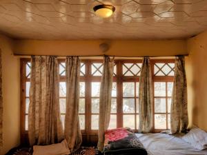 a bedroom with a large window with curtains at Hotel T-Suru Leh in Leh