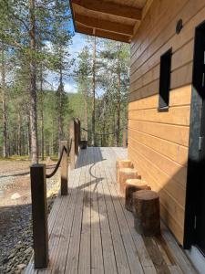 a wooden cabin with a wooden walkway in the woods at Lapin Unelma in Äkäslompolo