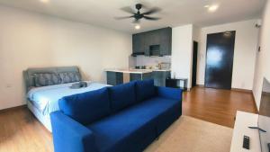 a living room with a blue couch and a kitchen at Eshue Designer Suites @ Simfoni Towers in Cheras