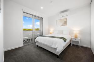 a white bedroom with a bed and a balcony at Elevated 2BR & Sofa Bed Apartment in the Heart of Prospect in Prospect