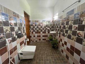 a bathroom with a toilet and a tiled wall at Green Valley in Kolakambe
