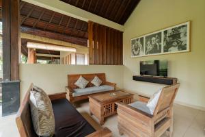 a living room with a couch and a tv at Budhi Ayu Villas and Cottages Ubud by Mahaputra in Ubud