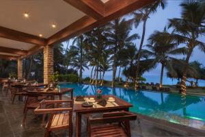 a restaurant with a pool and tables and palm trees at The Rockwall Boutique Hotel Bentota in Bentota