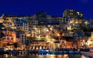 a city with boats in the water at night at Porta di Mare in Sciacca +28 photos