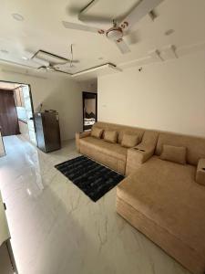 a living room with a brown couch and a kitchen at sun vacation resort in Visakhapatnam