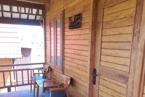 a wooden porch with two chairs and a door at Cozzy D'Sobahan Resort in Ngadirejo