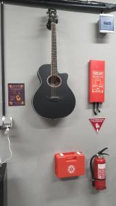 a guitar hanging on a wall with a red box at Yellow Monkey Hostel Uluwatu in Uluwatu